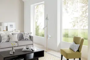 Living room with cream walls, chartreuse chair, low coffee table and oatmeal sofa with two large picture windows, undressed.