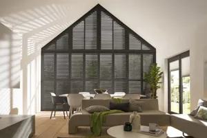 Gable end living/diner, stone fireplace to left, sofa beside, dark brown shutters, louvres open on gable end.