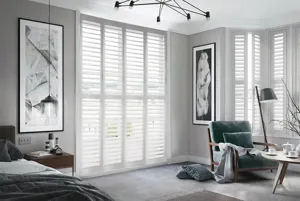 On a series of tall windows Chalk Dust Shutters have been fitted. The White colour suits the bedroom which is decorated in grey and wooden tones.
