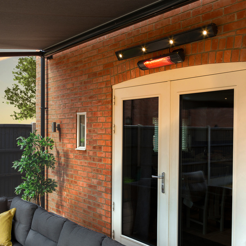 Exterior of red brick house showing the underside of a dark grey extended awning with a heater and a strip of lights mounted to the wall above a grey sofa with chartreuse cushion.