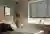 Tight shot of bedroom with one dark and one light brown wall, mid grey pleated blind three quarter lowered at window, bed with dusky pink head and foot, grey bedding, pink, brown and grey accessories.