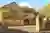 Large Yorkshire-style stone house and drive with integral garage door in mid brown matching front door, with climbing plant above garage.