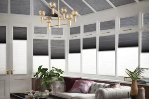 Conservatory with dark wood floor, pale grey sofa, dark grey roof blinds and side windows in twinshade blinds dark grey on top and white beneath, all at varying heights.