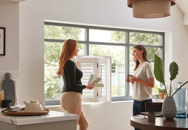 two people looking at shutter samples in front of a large kitchen window