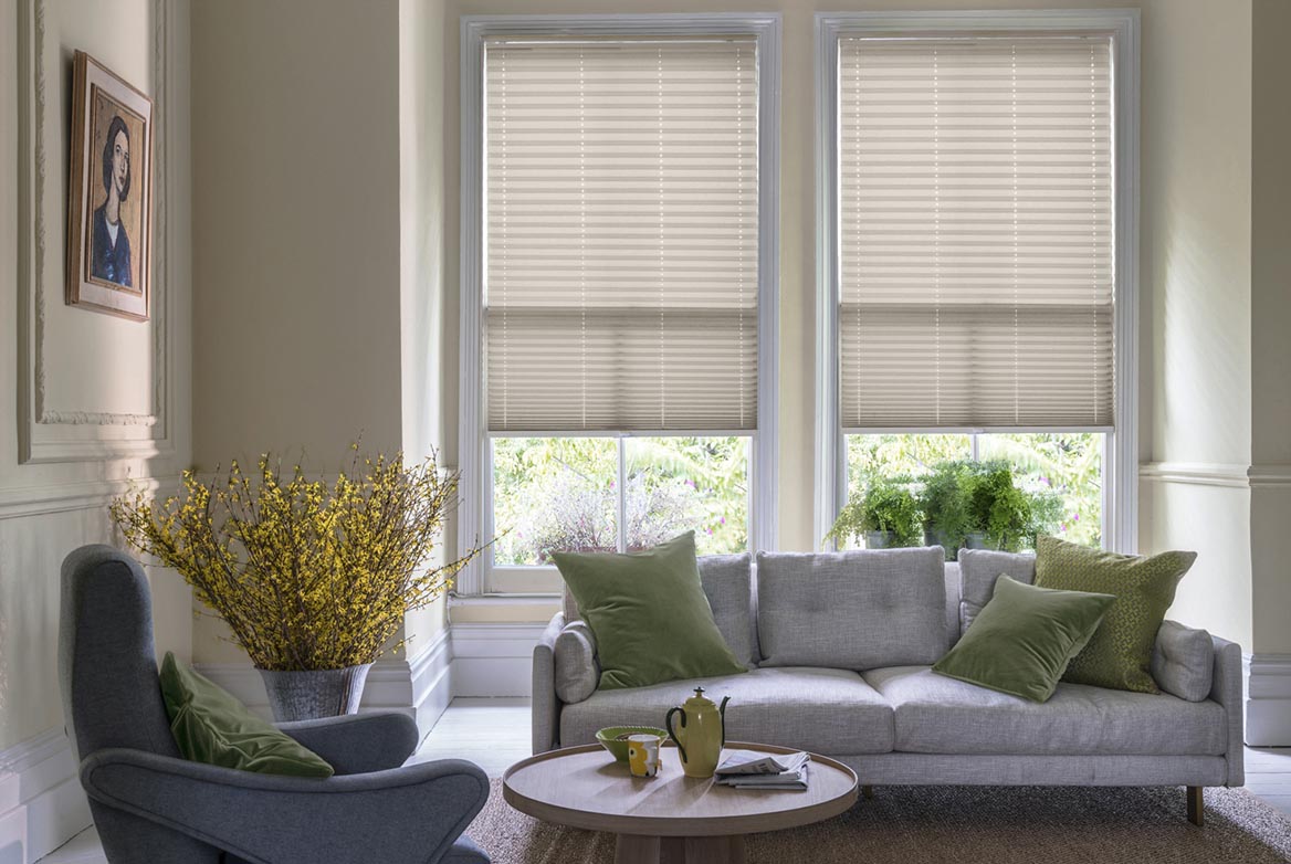 natural Pleated blinds have been fitted to multiple windows in a luxuriously styled kitchen in marble and white. Solartex Crush Truffle Crush has a plain style that complements the room.