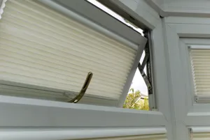 Close up of upper casement window, partially open, dressed in a cream duette blind, fitted to the frame. 