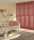 Living room in pale corn yellow with tall window dressed in full height shutters in salmon with sofa in pale peach with contrasting peach and salmon cushions.
