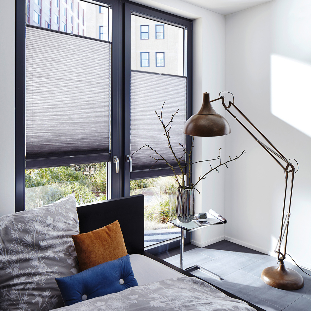 Two grey Duette blinds covering middle sections of doors, grey anglepoise lamp and vase with twigs. 