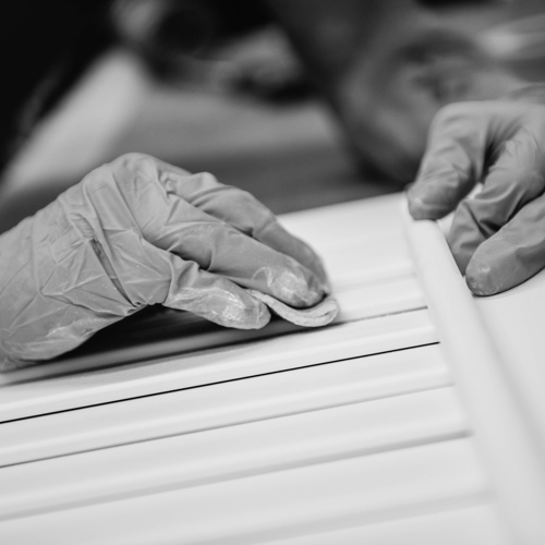 Close up of gloved hands making a shutter in a factory.