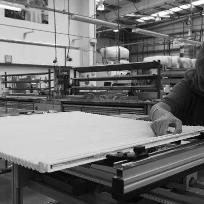 Black and white image of a man making an blind in a factory.