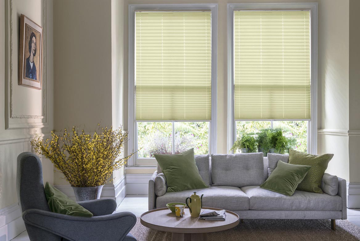 Decorated in a plain style California Sand Dune ivory Pleated blinds are fitted to windows in a kitchen with marble counter tops and cream coloured fixtures.