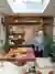 Dining area with rustic wooden table and benches underneath a roof lantern window, a woman with mobile in hand looks up.