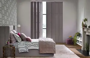 Mauve coloured solid tracked shutters fitted to a tall rectangular window in a bedroom decorative in repeating geometric designs