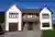 Large contemporary two-tone house with apex windows, integral garage with light brown garage door matching front door.