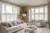 Neutral lounge with cream carpet and rug, pale grey sofa in front of window dressed with white tier on tier shutters, top half open, pale grey chair in a curved 5-bay window dressed in white shutters, louvres open.