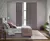 Solid tracked shutters in mauve, one partially open in a bedroom with pale mauve wall, geometric pattern wallpaper to left with mauve bed dressed in geometric bedspread with mauve throw, dark wood floor.