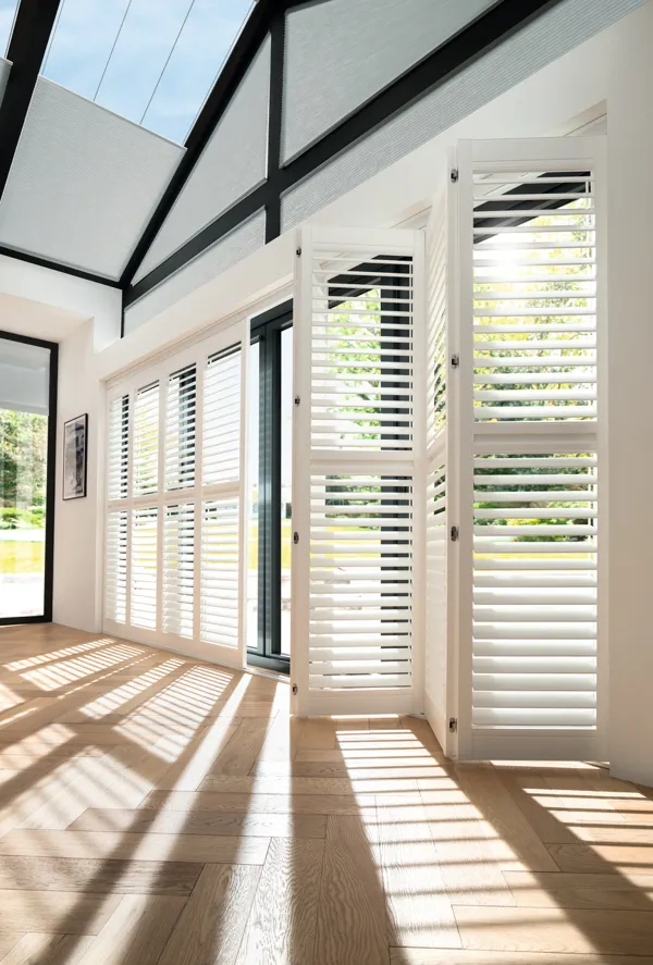 white vinyl shutters with open slats, tracked across a wall-long bifold door