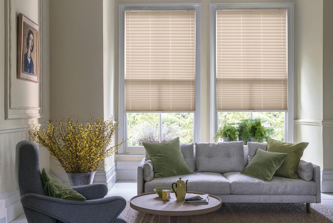 natural Pleated blinds have been fitted to multiple windows in a luxuriously styled kitchen in marble and white. Mara Oat has a plain style that complements the room.