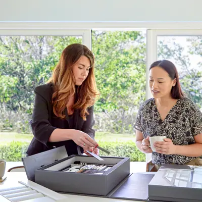 Two women standing at kitchen island looking at shutter samples.