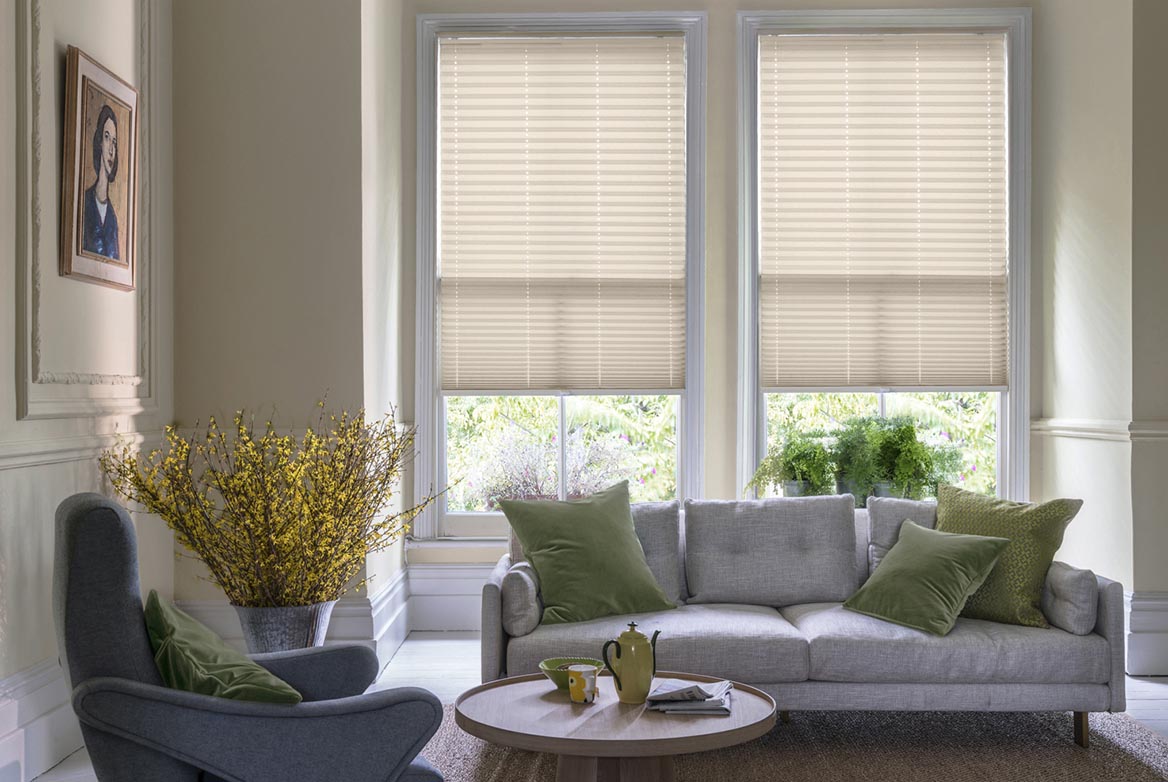 Decorated in a plain style Solartex Crush Stone Crush ivory Pleated blinds are fitted to windows in a kitchen with marble counter tops and cream coloured fixtures.