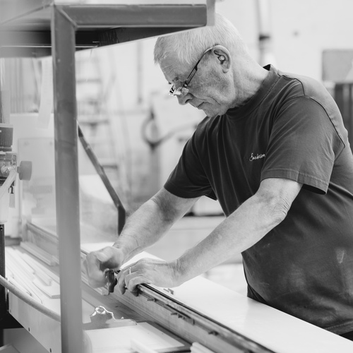 Black and white image of a man making a garage door in a factory.