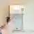 A finger presses the down button of a garage door electric wall control with a light on it and a couple of buttons.