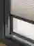 Close up of the bottom of a dark brown sliding door frame dressed with an ivory pleated blind lowered just short of the frame.
