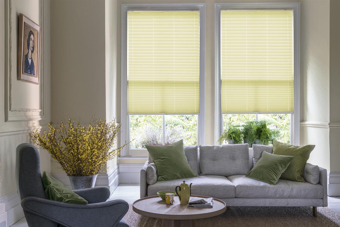 Fitted to multiple windows in a marble and white decorated kitchen are Tosca Corn Pleated blind. The stripe design of these yellow Pleated blinds completes the look.
