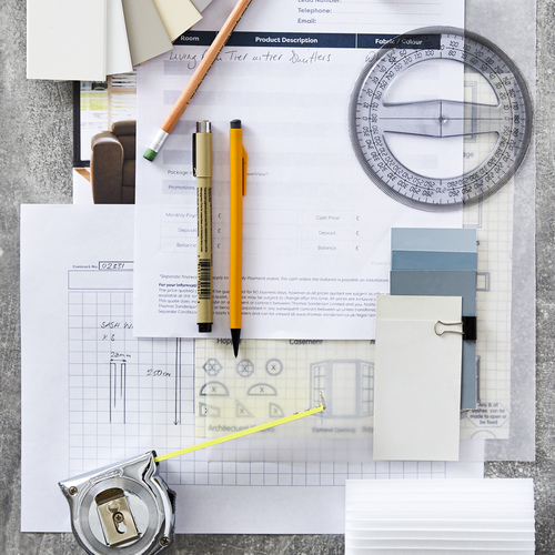 Moodboard-style flatlay with circular protractor, pencils, graph paper, small samples of wood in whites and cream, marine-coloured paint card samples, a steel tape measure and a ruler.
