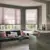 Contemporary kitchen with banquette seating under bay windows dressed in soft pink Duette blinds drawn halfway, co-ordinating cushions on blue seating, kitchen counters in soft grey with white top.