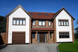 Large contemporary two-tone house with apex windows, integral garage with light brown garage door matching front door.