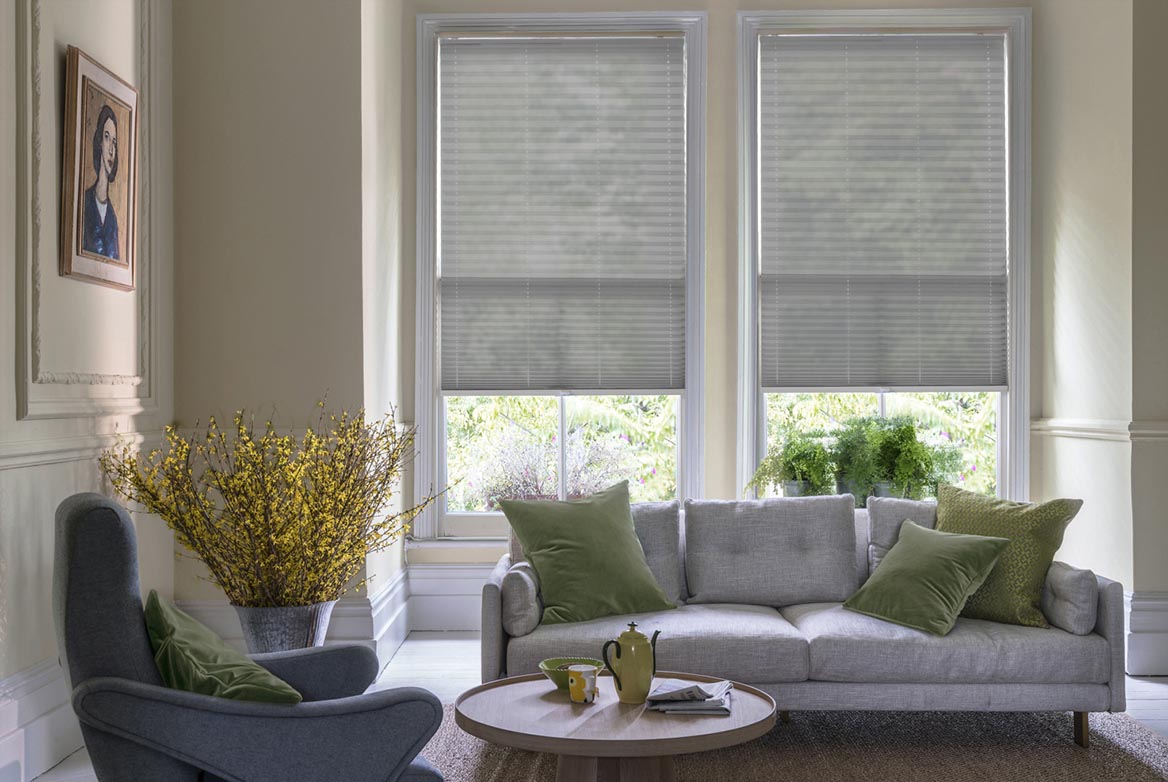 grey Pleated blinds have been fitted to multiple windows in a luxuriously styled kitchen in marble and white. Lumina Sheer Steel has a plain style that complements the room.