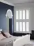 white shutters in navy blue living room with arched doorway and white bed