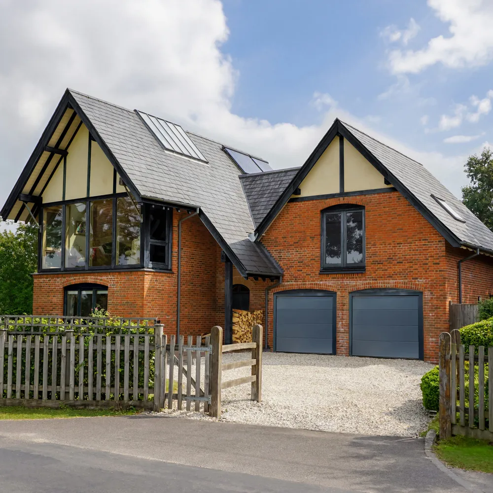 Large house with attached garage and second storey block with two grey sectional garage doors.