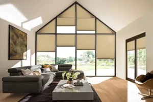 Living area with grey sofa and low table on a rug over a wooden floor with gable end window dressed in pale caramel duette blinds at varying levels.