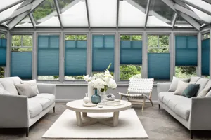 Large conservatory  with pale grey sofas facing over a low white round table, with roof windows open, dressed in grey pleated blinds and azure blue side blinds at varying heights.