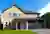 Yellow Cotswold stone-style house with integral  garage with two blue steel garage doors that match the front door.