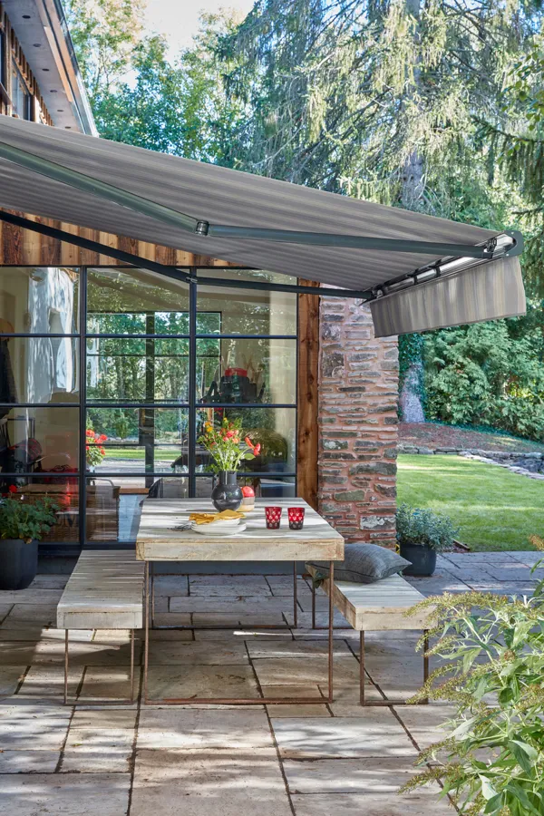 Tebbutts awning hanging over the patio in their garden with benches and a table