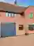 An orange brick house with a balcony, anthracite grey window frames and an anthracite grey roller garage door.