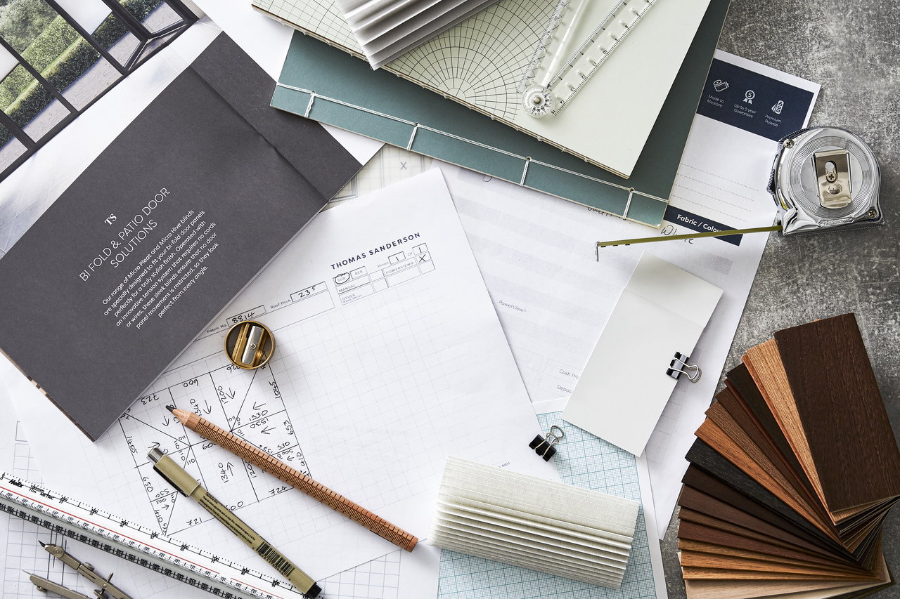 Pen, pencil, ruler, stencils, measuring tape and fabric swatches on a table